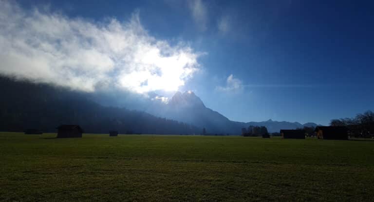 Blick über die Degernau von Garmisch-Partenkirchen Richtung Grainau mit Bergpanorama: Waxensteine und den österreichischen Bergen. Wolken verdecken die Sonne